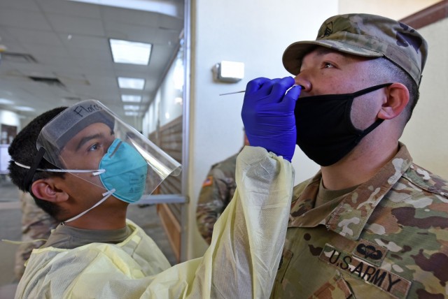 Pvt. Daniel Flores with Alpha Company, 232nd Medical Battalion, uses a cotton swap to test Staff Sgt. Jose Gomez with Alpha Company 264th Medical Battalion for COVID-19.