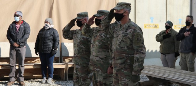 As members of the USACE Afghanistan District stand in the background, the Command Team salutes during the playing of the National Anthem during the Casing of the Colors Ceremony.