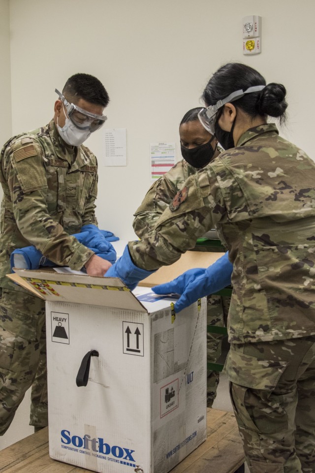 Airman 1st Class Raymond De Jesus, 59th Medical Wing medical logistics technician, and Staff Sgt. Romina Guridi, 59th MDW medical logistics warehouse supervisor, open the San Antonio Military Health System’s first Pfizer COVID-19 vaccine shipment, Dec. 14, 2020, at Wilford Hall Ambulatory Surgical Center, Joint Base San Antonio-Lackland, Texas. The Department of Defense aims to be able to reduce the burden of the COVID-19 disease in high-risk populations and simultaneously mitigate risk to military operations. (U.S. Air Force photo by Airman 1st Class Melody Bordeaux)