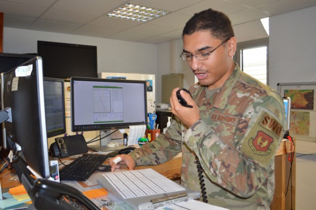 Senior Airman Christopher Ware, forecaster, Detachment 4, 7th Combat Weather Squadron, gives a weather brief over the radio to an aviator preparing for takeoff at Katterbach Army Airfield, Germany. Ware and eight other Airmen are attached to the 12th Combat Aviation Brigade providing decision-grade weather intelligence and combat-credible forces.