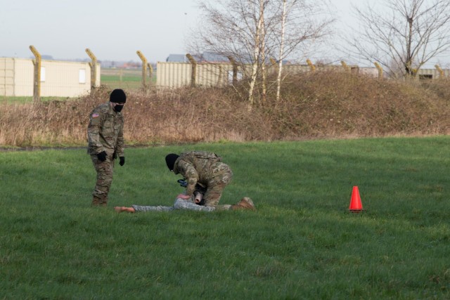 U.S. Army Staff Sgt. Jacob Beaudoin, left, oversees Sgt. Michael Sanabria, a U.S. Army Garrison Benelux MP assigned in Brunssum, Netherlands, as he prepares a simulated casualty for a medical evacuation for the medical lane of the Best Warrior...