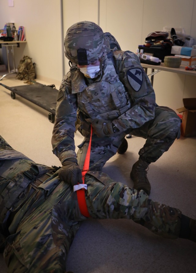 Pfc. Lucas Buchanan, a medic assigned to Headquarters, Headquarters Company, 2nd Battalion, 8th Cavalry Regiment, places a tourniquet to a simulated casualty suffering a notional leg amputation during Tactical Combat Casualty Care assessments Jan....
