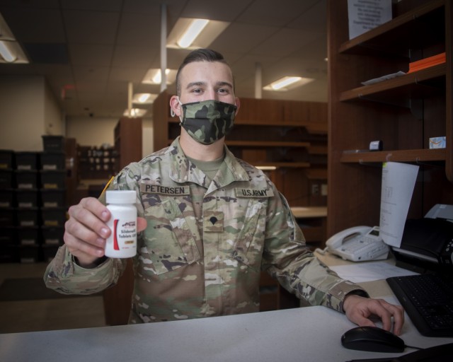 Army Spc. John Petersen, pharmacy technician, hands a prescription to a beneficiary at the Community Pharmacy in the Exchange, Fort Sam Houston, Texas, Feb. 1, 2021. On average, new prescriptions take about 30 minutes to fill. For prescription refills customers generally wait about 2 minutes for pick up. (U.S. Army photo by Jason W. Edwards)