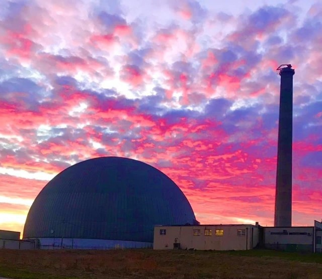 The stack standing next to a domed building that is part of the decommissioned High Flux Beam Reactor.