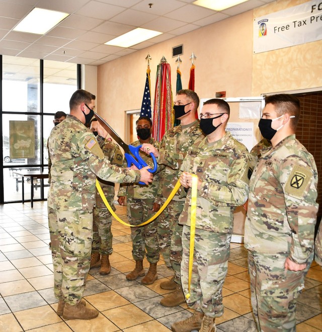 Spc. Devin Buterbaugh, 46th Engineer Battalion and volunteer tax preparer at the Fort Polk Tax Center, hands Brig. Gen. David S. Doyle, Joint Readiness Training Center and Fort Polk commanding general, a large pair of scissors in advance of the...