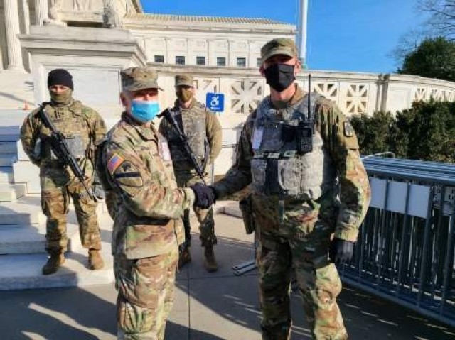 Staff Sgt. Kyle Runyon of Topeka, Kansas, noncommissioned officer in charge of Task Force Kansas, the contingent of Kansas Guardsmen sent to the U.S. Capital region, receives a coin from Brig. Gen. John Driscoll, task force commander for Capitol...