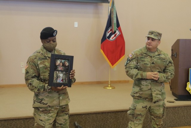 Sgt. 1st Class Ruben Gonzalez (right), an observer coach trainer for 1st Battalion, 337th Brigade Support Battalion, 181st Infantry Brigade, presents a photo of Sofia (daughter) and family to Command Sgt. Maj. Ernest Peterson Jan. 22, at Fort McCoy, Wis., for helping his family during the passing of his daughter last December. 