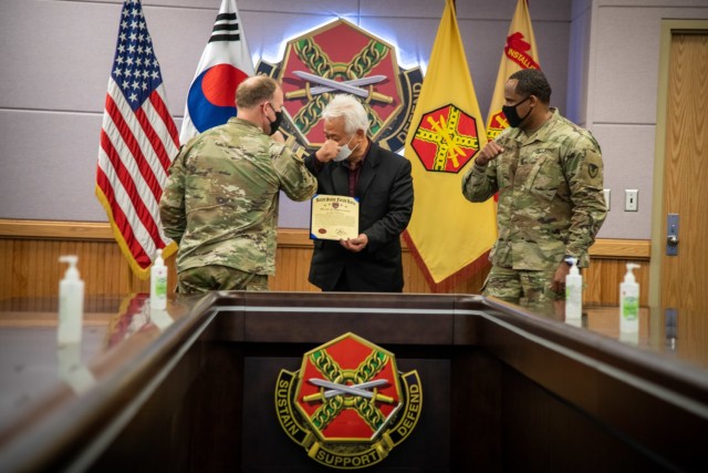 CAMP HUMPHREYS, Republic of Korea - Col. Michael F. Tremblay, left, the commander of United States Army Garrison Humphreys, and Command Sgt. Maj. Benjamin Lemon, the senior enlisted advisor for USAG-Humphreys, right, bump arms and congratulate Mr. Woo, Jong Mok, a Good Neighbor at Humphreys and President of the Songtan-Osan Community Leaders Association, for winning the Good Neighbor Award – Individual (Korean) for 2020 during the virtual 2020 United States Forces Korea Good Neighbor Award Competition, Feb. 1. Woo has been a Good Neighbor at Humphreys since 2014 and has hosted cultural and appreciative events for Soldiers and families here, demonstrating the importance of cultural exchange and the continued support for the alliance between the United States and the Republic of Korea. (U.S. Army photo by Spc. Matthew Marcellus)