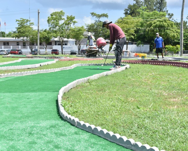 To the delight and enjoyment of enrolled children, the grounds next to the Fort Buchanan Child Youth Center (CYS), is now a miniature golf course.  Child and Youth Services Program Professional, José Martinez tries out a putt, as he and the staff prepared the nine holes, they tested them for flow and complexity as they constructed the course.