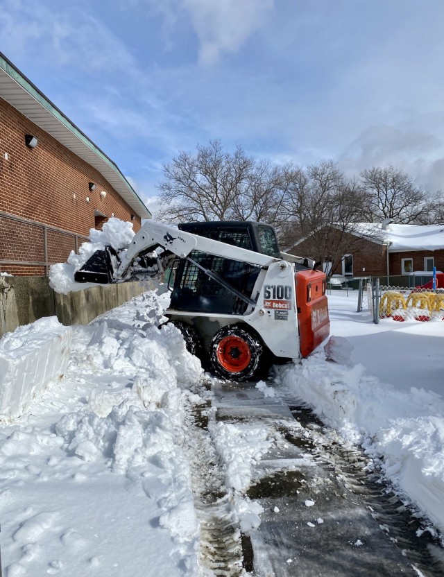 A skid steer clears snow out of the Child Development Center area on Fort Hamilton, N.Y., Feb. 3, 2021. A major winter storm struck the Mid-Atlantic and Northeast, creating near-blizzard conditions along the coast, forcing many to stay home and...