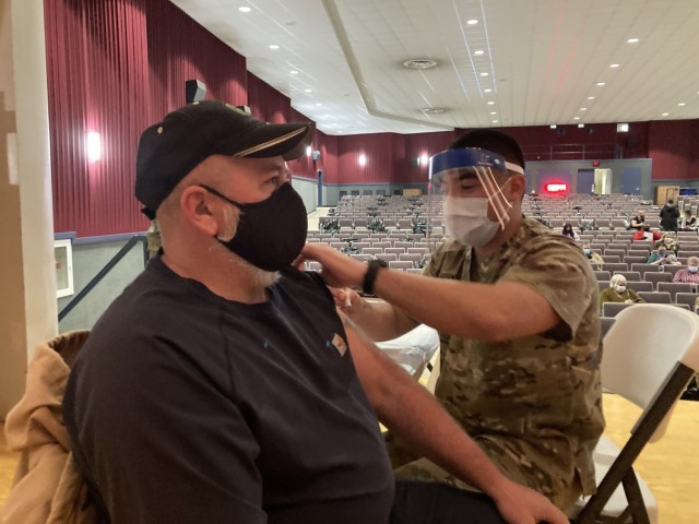 Specialist George Bahena, a medic with 2nd Battalion, 506th Infantry Regiment, 3rd Brigade Combat Team, 101st Airborne Division (Air Assault), prepares to administer a COVID-19 vaccine Jan. 22 to Kyle Jerkins, supervisor of Roads and Grounds, and Landfills, Directorate of Public Works, at Wilson Theater.