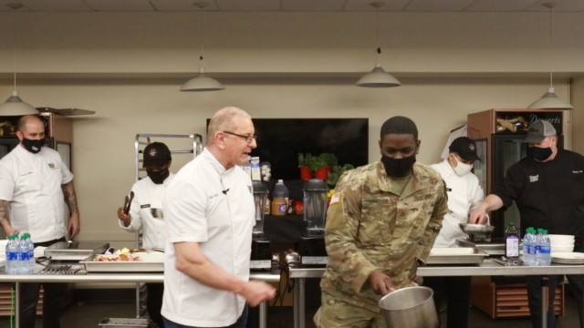 Chef Robert Irvine demonstrates proper cooking techniques with culinary specialists from the 1-2 Stryker Brigade Combat Team during a cooking demonstration at the Ghost Inn warrior restaurant on Joint Base Lewis-McChord, Washington, Jan. 25, 2021....