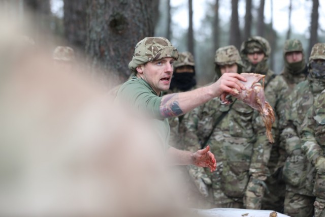 Instructor from the U.K. Land Warfare Center teaches  U.K. Troops from NATO enhanced Forward Presence Battle Group Poland shows off a plucked bird as he teaches Soldiers how to procure food in the wild during a cold weather operator's course Dec....