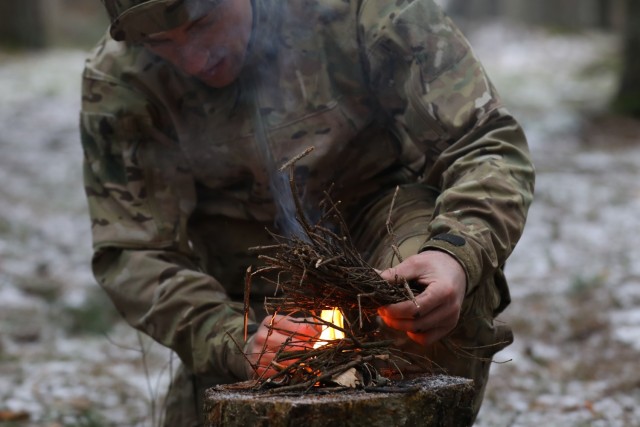 Instructor from the U.K. Land Warfare Center demonstrates a method for building a fire from items found in the environment for U.K. Troops from NATO enhanced Forward Presence Battle Group Poland  during a cold weather operator's course Dec. 11,...
