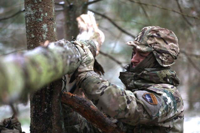 U.K. Army Soldier from enhanced Forward Presence Battle Group-Poland constructs a crude shelter during a cold weather survival course Dec. 11, 2020 at Bemowo Piskie Training Area, Poland. (U.S. Army photo by Staff Sgt. Elizabeth O. Bryson)