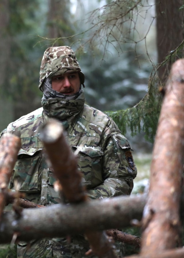 British Trooper from enhanced Forward Presence Battle Group-Poland discusses the construction of an overnight shelter during a cold weatheroperator's course Dec. 12, 2020 at Bemowo Piskie Training Area, Poland. (U.S. Army photo by Staff Sgt....