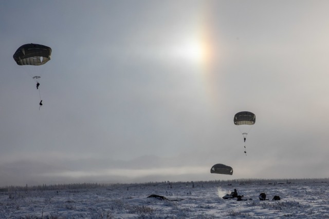 Paratroopers with 3rd Battalion, 509th parachute infantry regiment, 4th Infantry Brigade Combat Team (Airborne), 25th Infantry Division, descend from the sky during an airfield-seizure operation at Donnelley Training Area, Alaska, Feb., 7, 2021. Paratroopers will spend approximately ten days in the Alaskan cold conducting a near-peer combat scenario beginning with an airborne operation to secure an airfield. (U.S. Army photograph by Staff Sgt. Alex Skripnichuk)