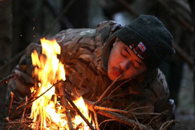 U.K. Army Soldier from enhanced Forward Presence Battle Group-Poland breathes air into a fire during a cold weather survival course Dec. 11, 2020 at Bemowo Piskie Training Area, Poland. (U.S. Army photo by Staff Sgt. Elizabeth O. Bryson)