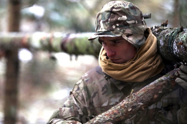 U.K. Army Soldier from enhanced Forward Presence Battle Group-Poland helps build an overnight shelter during a cold weather survival course Dec. 11, 2020 at Bemowo Piskie Training Area, Poland. (U.S. Army photo by Staff Sgt. Elizabeth O. Bryson)