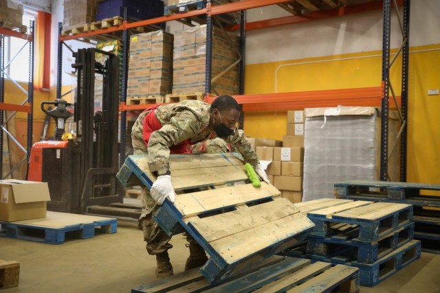 Spc. Bobbie Williams, Headquarters, Headquarters Company, 2nd Battalion, 8th Cavalry Regiment, moves a wooden pallet after cleaning it Feb. 4, 2021. Williams volunteered his time at the Maistobankas (food bank) in Vilnius, Lithuania. In addition to help cleaning the warehouse, he also helped pack 100 food parcels that will be distributed to home bound residents. (U.S. Army photo by Sgt. Alexandra Shea)