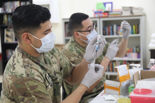 Spc. Michael Meza and Spc. John Cera, healthcare specialists with the 228th Combat Support Hospital, draw doses of the Moderna COVID-19 vaccine from vials at Camp Arifjan, Kuwait, Jan. 18, 2021. Camp Arifjan is utilizing a phased distribution of...