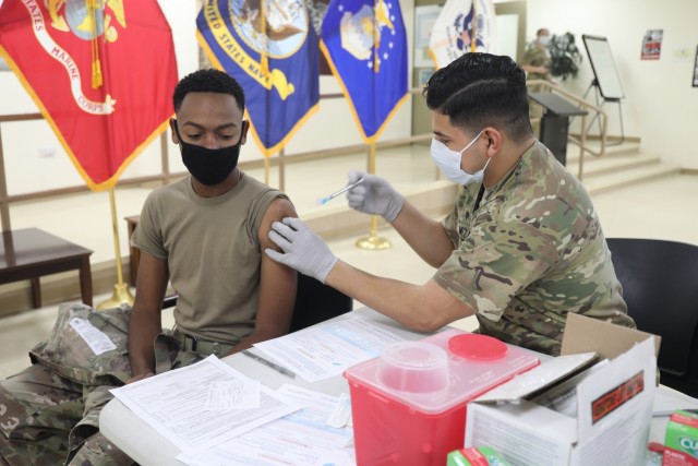 Spc. Michael Meza, healthcare specialist, 228th Combat Support Hospital, administers the Moderna COVID-19 vaccine to Spc. Sarrod Hearn, radiology specialist, 228th Combat Support Hospital, at Camp Arifjan, Kuwait, Jan. 18, 2021. Camp Arifjan is...