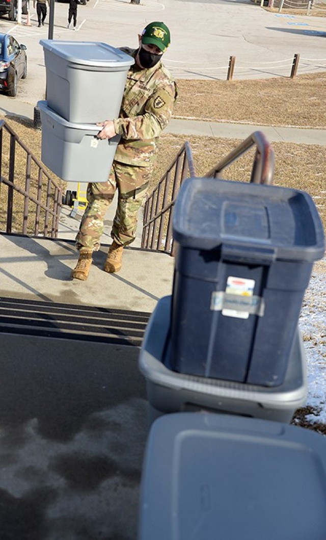 Chaplain (Capt.) Mike Troutt carries bins filled with donated children's clothing from the temporary collection site to what will become the Justice Closet for new parents in the 15th MP Brigade to use Feb. 5 at the 40th Military Police Battalion...