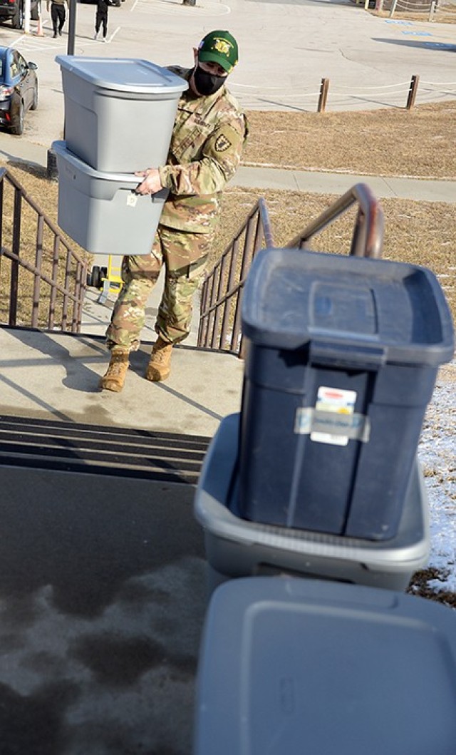 Chaplain (Capt.) Mike Troutt carries bins filled with donated children's clothing from the temporary collection site to what will become the Justice Closet for new parents in the 15th MP Brigade to use Feb. 5 at the 40th Military Police Battalion (Detention) buildings. Photo by Prudence Siebert/Fort Leavenworth Lamp