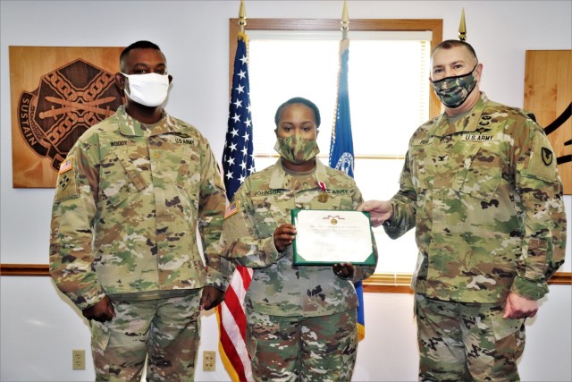 Fort McCoy Garrison Commander Col. Michael D. Poss (right) presents Master Sgt. Cynthia P. Johnson with an Army Meritorious Service Medal on Jan. 22, 2021, at the garrison headquarters building at Fort McCoy, Wis. Johnson earned the medal for meritorious service with Fort McCoy Garrison between 2018 and 2021. Also pictured is Maj. Eddie Woody, Fort McCoy Garrison Headquarters and Headquarters Company commander. (U.S. Army Photo by Scott T. Sturkol, Public Affairs Office, Fort McCoy, Wis.)