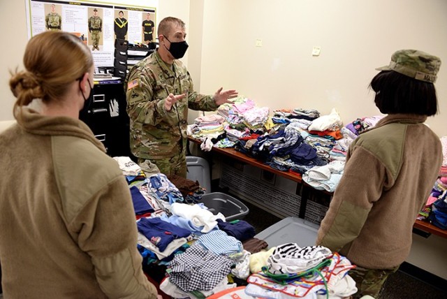 Chaplain (Capt.) Mike Troutt explains to Pvt. Anna Gram and Pvt. Monique Mason, 291st Military Police Company, 40th Military Police Battalion (Detention), how he would like pre-sorted children's clothing packed into bins to transfer the donations from a temporary collection site to what will become the permanent closet in a nearby building Feb. 5 at the 40th MP Battalion Headquarters. Photo by Prudence Siebert/Fort Leavenworth Lamp