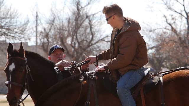 Gerald Stuck, Artillery Half Section chief, corrects the grip of new rider, Sgt. Jacob Ferguson Feb. 2, 2021, on the Old Post Quadrangle at Fort Sill, Oklahoma. Ferguson was one of the new riders learning how to control a pair of horses.