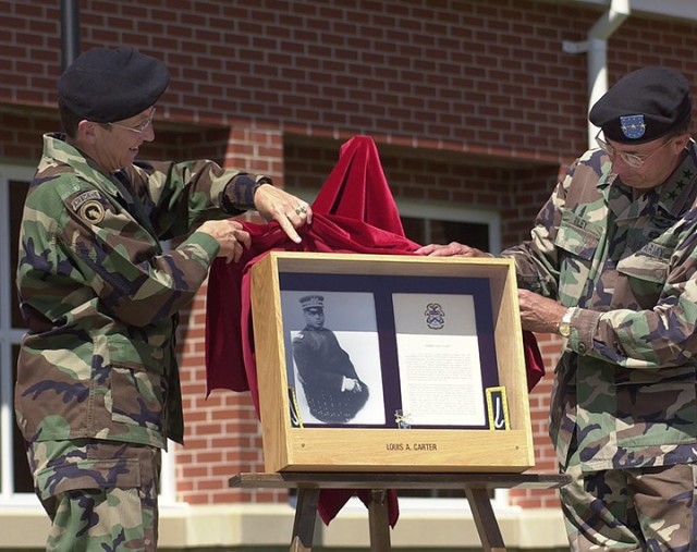 Combined Arms Center Command Sgt. Maj. Cynthia Pritchett and Combined Arms Center and Fort Leavenworth Commander Lt. Gen. James Riley unveil the shadowbox containing Chaplain (Col.) Louis Carter’s photo and brief biography at the Single Soldier Quarters dedication May 30, 2003. In addition to Carter, wings in the building were named for Sgt. Maj. William McBryar, Sgt. Maj. Lacey Ivory, Capt. Chester Lee and Pfc. Vernon Janzen. Photo by Prudence Siebert/Fort Leavenworth Lamp