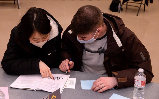 Emika Okada and her husband Capt. Stephen Nitkowski, Command and General Staff Officer Course student, take a few minutes between video segments to work on an exercise in their workbook during lesson one, "The Elusive Secret," of the "Vertical...