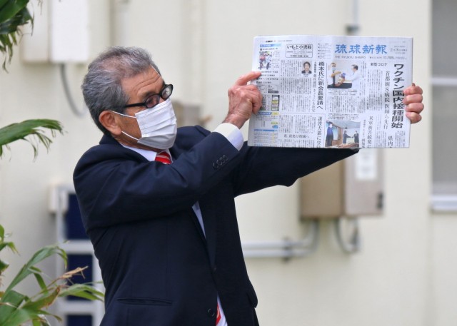 Tsutomu Nakasone, an Okinawa Area Office project manager with the Project Management Branch and 25+ year U.S. Army Corps of Engineers Employee, holds aloft a local Okinawan newspaper that he will place in the USACE 75th Anniversary time capsule....
