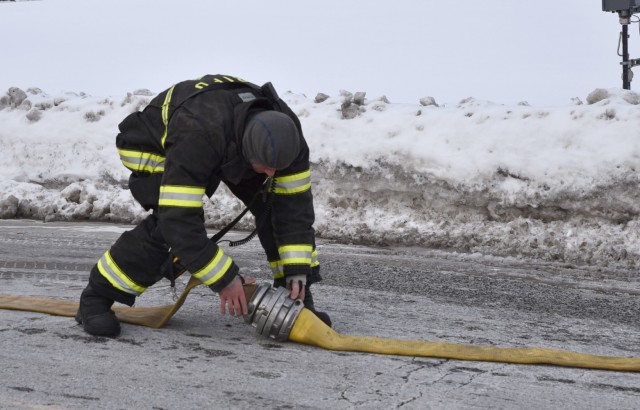 A Rock Island firefighter connects a hose in order to quickly gain access to the fire hydrant system to fight the blaze in a residence’s attic.