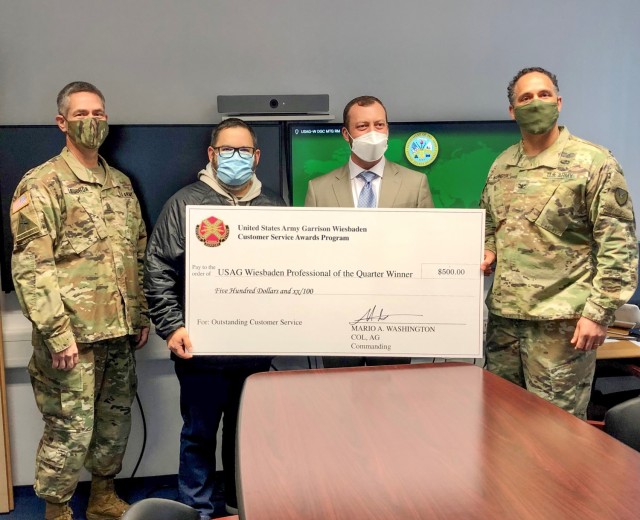 Garrison Commander Col. Mario Washington, accompanied by Command Sgt. Maj. Christopher Truchon and Scott Mowry, deputy to the garrison commander, issue the $500 award and certificate of recognition to Oswaldo Melendez, director Information...