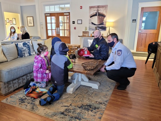 Assistant Fire Chief Steve Larue and Fire Inspector Rob Gates hand out plastic fire helmets to children playing at the Crescent Woods Community Center before the Coffee with the Chiefs event Feb. 23. (Photo by Mike Strasser, Fort Drum Garrison Public Affairs)