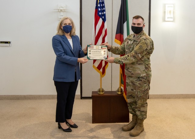 Ambassador Alina L. Romanowski, United States ambassador to Kuwait, presents a certificate of appreciation to 1st Lt. Mitchell Mackesey, medical operations and logistics officer, 310th Expeditionary Sustainment Command, for his efforts in providing life-saving measures and assisting a local victim of a catastrophic vehicle accident in Kuwait City, Kuwait, Feb. 18, 2021. (U.S. Army Photo by Spc. Zoran Raduka, 1st TSC Public Affairs)