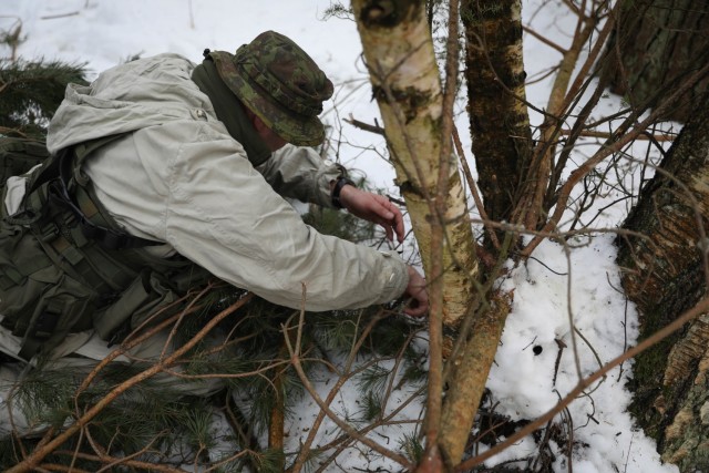 Lithuanian Volunteer Force Lt. Eimantas Maslauskas places an improvised explosive device along a tank trail Feb. 21, 2021, at the Kairai Training Area. Maslauskas and his team of five placed several ambushes along the trail to test the ability of his team to halt or stop enemy heavy weaponry movement. (U.S. Army photo by Sgt. Alexandra Shea)