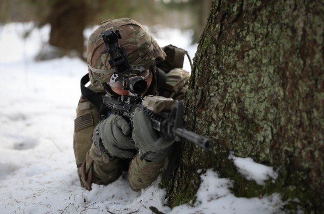 Pfc. Dakota Spautz, a dismount infantryman assigned to 2nd Battalion, 8th Cavalry Regiment, 1st Armored Brigade Combat Team, 1st Cavalry Division, takes cover behind a tree as he scans the area in front of him for 'enemy soldiers.' Spautz was one of several 2-8 Cav. Reg. Troopers to take part in a combined training exercise with Lithuanian Land Forces Feb. 21, 2021, at the Kairai Training Area. Lithuanian forces emplaced ambushes along a two-mile route the U.S. forces traveled to test their ability to identify and react to the ambushes. (U.S. Army photo by Sgt. Alexandra Shea)