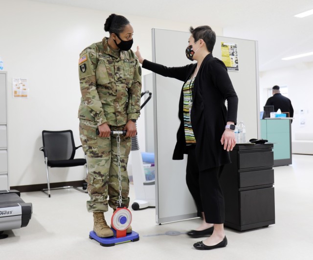 Shannon Vo, right, director of the Camp Zama Army Wellness Center, shows U.S. Army Medical Department Activity – Japan Command Sgt. Maj. Tanya Boudreaux, how to hold her back for the center’s back-strength test at the Camp Zama AWC in Bldg. 379, Camp Zama, Japan, Feb. 25.