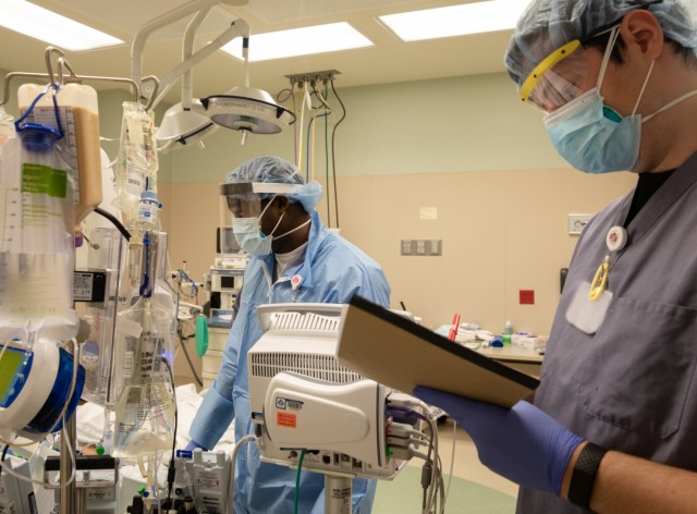 Sgt. Juraill Simpson, a respiratory therapist assgined to Urban Augmentation Medical Task Force - 531, left, and a civilian colleague check in on a patient at Marshfield Medical Center in Eau Claire, Wisc., Dec. 16, 2020. U.S. Northern Command, through U.S. Army North, remains committed to providing flexible Department of Defense support to the Federal Emergency Management Agency in support of the whole-of-America COVID-19 response. (U.S. Army photo by Spc. John Weaver)