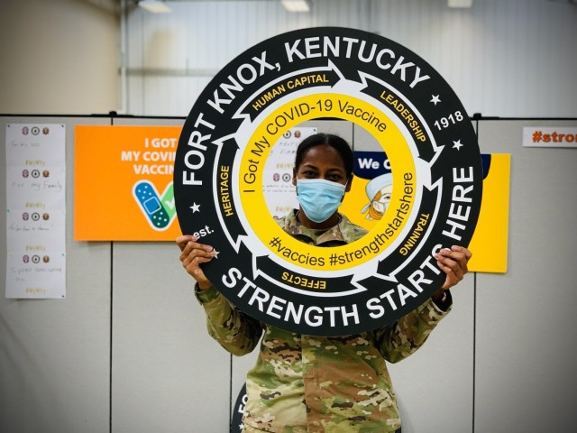 After receiving her vaccination shot, Capt. Lauren Dodd holds up a motivational prop and smiles 25 Feb 2021 at the Fort Knox vaccination site.