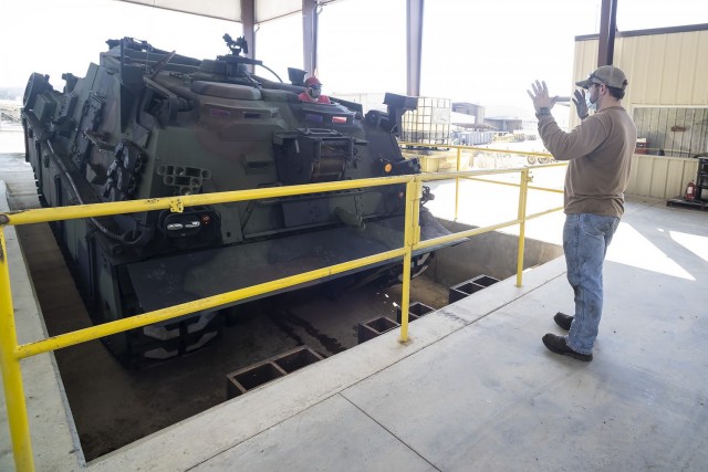 Matthew Shears, heavy mobile equipment mechanic, guides Joel Henderson, HME mechanic, as he drives a M88A2 into the test pit. The pit helps to keep the vehicle level with the anchor winch during testing.