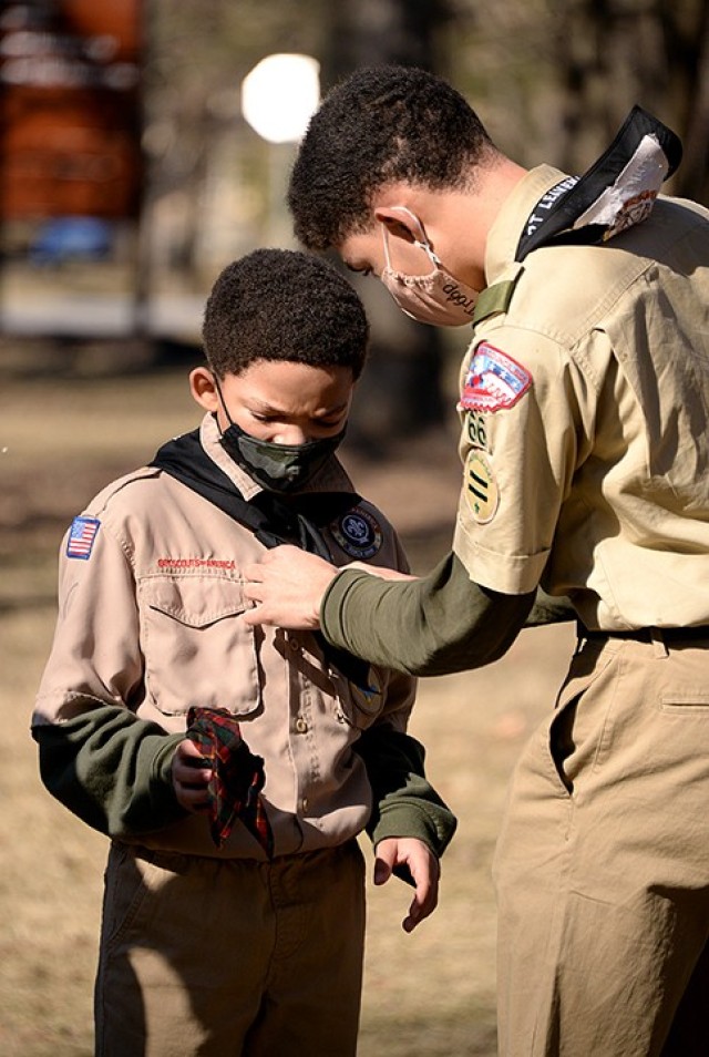 Ten-year-old Rohan Johnson holds his Webelos neckerchief as his brother, 15-year-old Roman Johnson replaces it with a Troop 66 neckerchief during the Cub Scouts to Scouts BSA crossover ceremony Feb. 27 at Zais Park. Photo by Prudence Siebert/Fort...