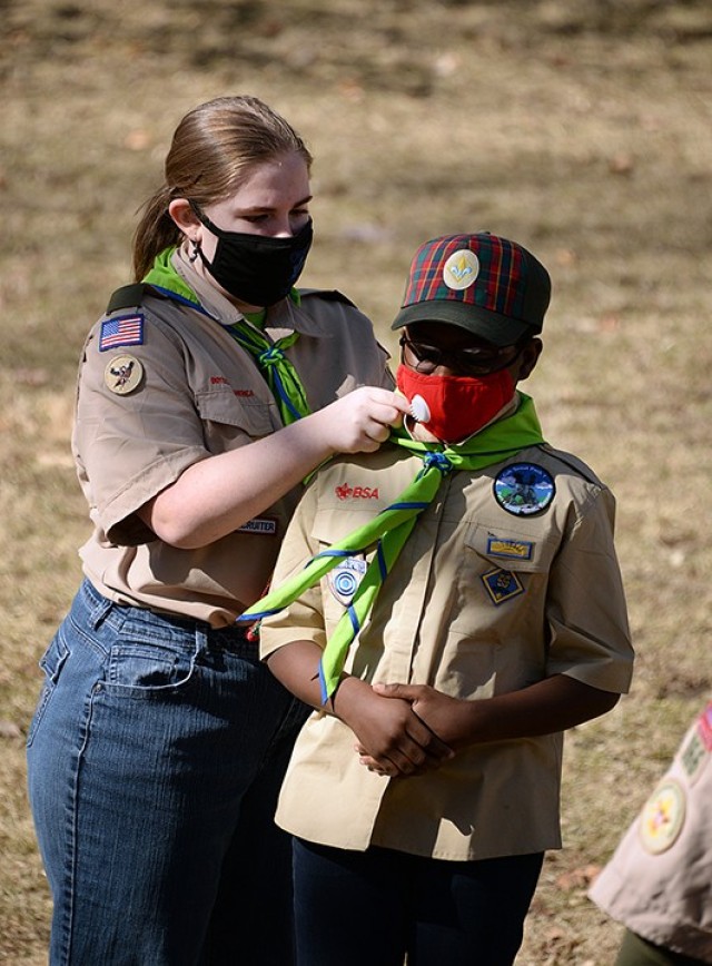 Acting Senior Patrol Leader Eliza Resch welcomes 10-year-old Marianna Klutse into Troop 166 with the troop's bright green neckerchief during the Cub Scouts to Scouts BSA crossover ceremony Feb. 27 at Zais Park. Photo by Prudence Siebert/Fort...