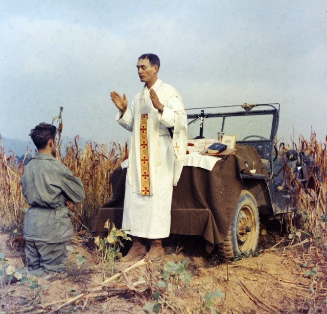 Father Emil Kapaun celebrates Mass using the hood of his jeep as an altar, as his assistant, Patrick J. Schuler, kneels in prayer in Korea on Oct. 7, 1950, less than a month before Kapaun was taken prisoner. Kapaun died in a prisoner of war camp on May 23, 1951. 