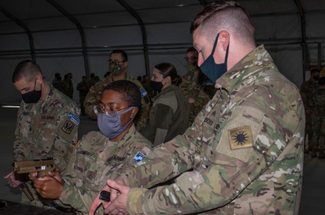 Sgt. Abraham Boxx, a critical care flight paramedic, teaches Pfc. Mariyah Berry, an automated logistical specialist, both assigned to Regional Command-East, Kosovo Force, how to handle a Sig Sauer M17 pistol during an aviation stand down at Camp...