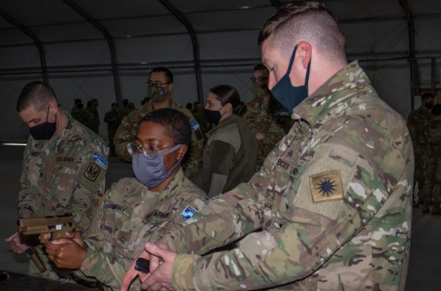 Sgt. Abraham Boxx, a critical care flight paramedic, teaches Pfc. Mariyah Berry, an automated logistical specialist, both assigned to Regional Command-East, Kosovo Force, how to handle a Sig Sauer M17 pistol during an aviation stand down at Camp Bondsteel, Kosovo, on March 6, 2021. Hands-on instruction allows Soldiers to gain familiarity with weapon systems they haven’t used before in a safe environment. (U.S. Army National Guard photo by Sgt. Jonathan Perdelwitz)