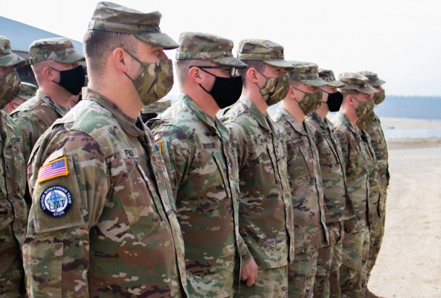 Iowa Army National Guard Soldiers assigned to the Kilo 18 liaison monitoring team, Regional Command-East, Kosovo Force, stand in formation during a recognition ceremony at Camp Bondsteel, Kosovo, on March 8, 2021. Sgt. Spenser Sharp and Spc. Cole Magnuson were awarded Ryder Brigade coins to honor them for going out of their way to help Kosovo civilians in an emergency. (U.S. Army National Guard photo by Sgt. Jonathan Perdelwitz)